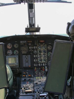 Back view anonymous male military pilots wearing khaki uniform in cockpit and helmets flying armed helicopter