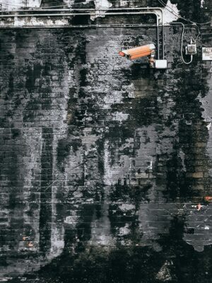 CCTV camera hanging in grungy weathered wall on street